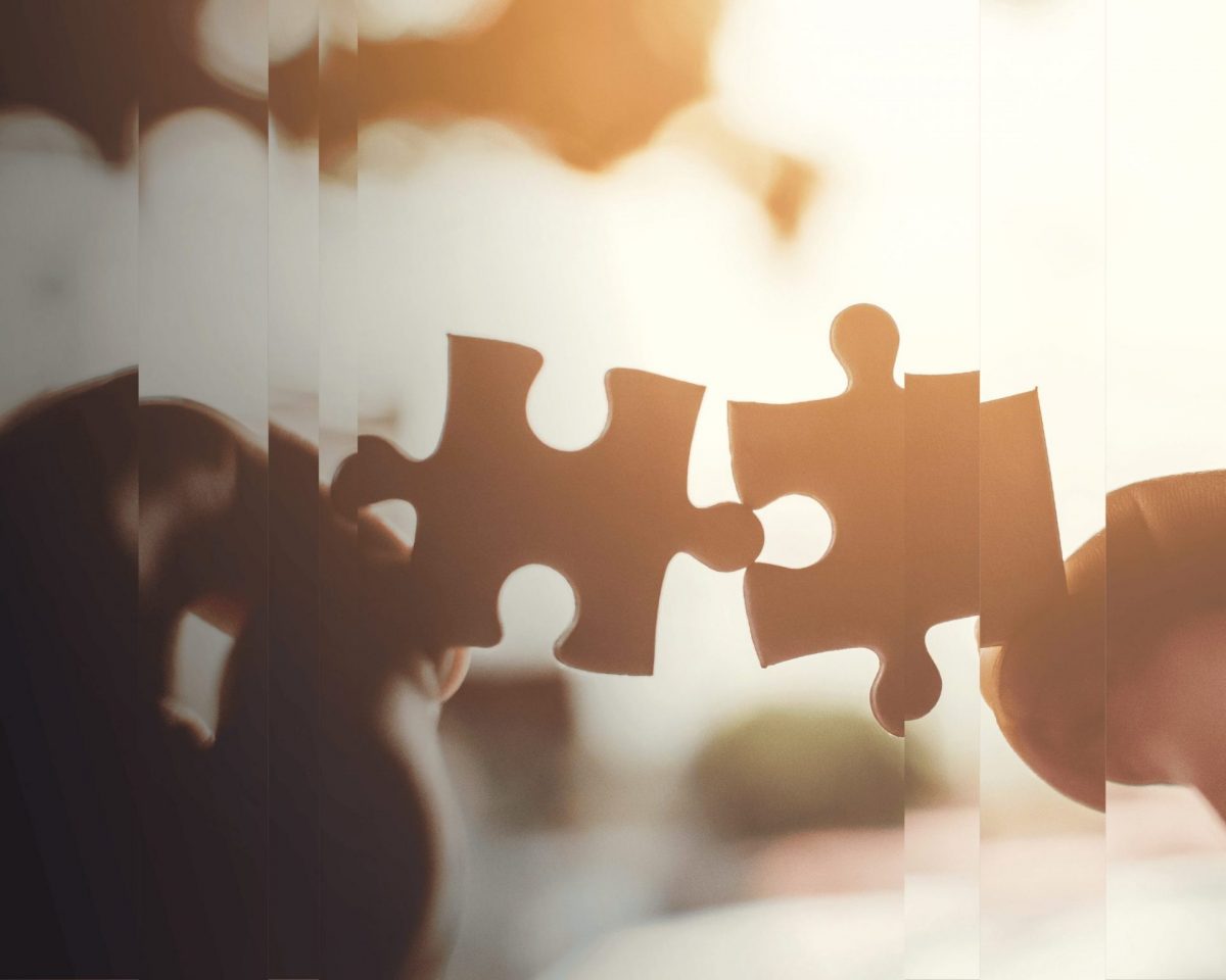 Hands holding two pieces of puzzle, representing family office technology solutions for better wealth management.