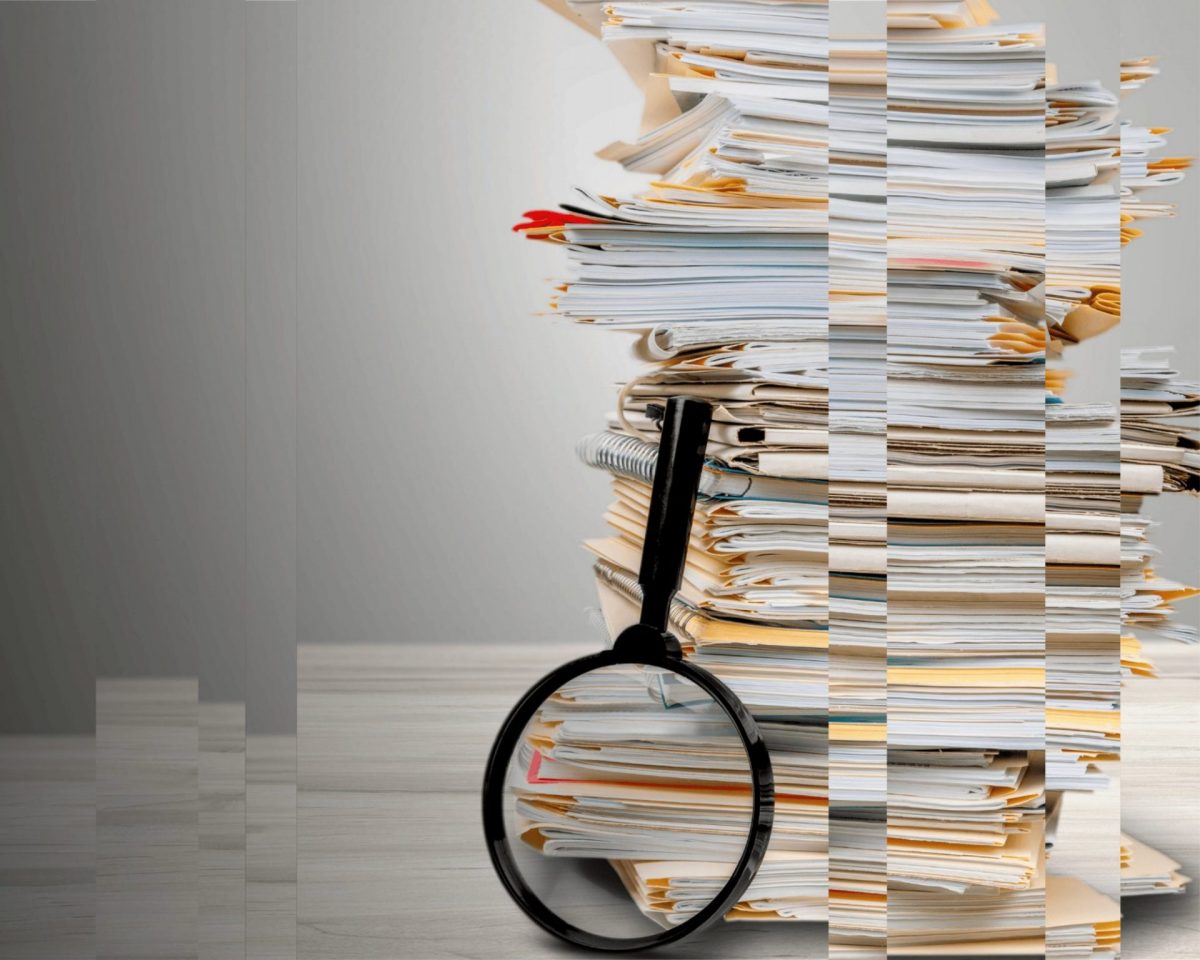 A picture of a stack of files and a magnifying glass, representing the need for good digital record-keeping practices to simplify records.