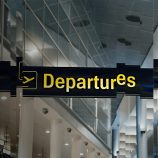A distorted image of the departures sign at an airport to signify exit taxes, the topic of the article.